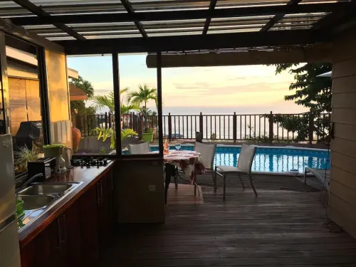 An outdoor kitchen and sitting area in front of a patio pool area in Tahiti, French Polynesia